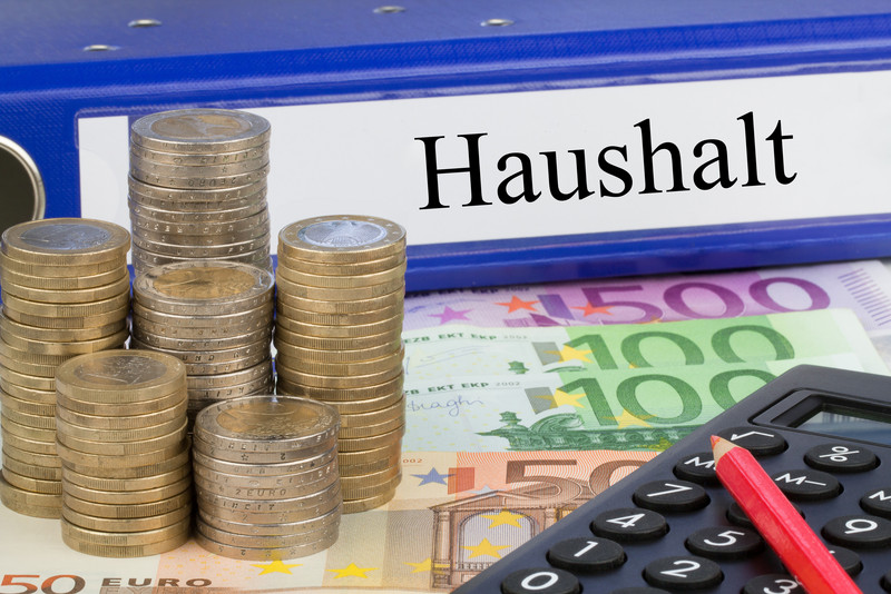 Haushaltsordner, Münzen und ein Taschenrechner
