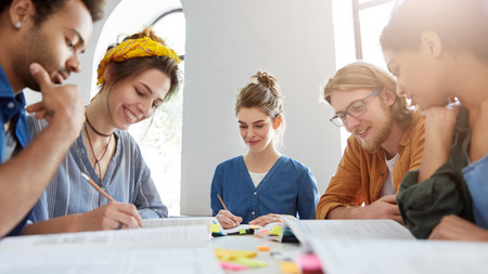 Gruppe von Jugendlichen, die an einem Tisch sitzen und miteinander diskutieren