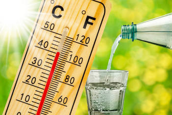 Thermoeter zeigt 40 Grad an und ein Glas Wasser