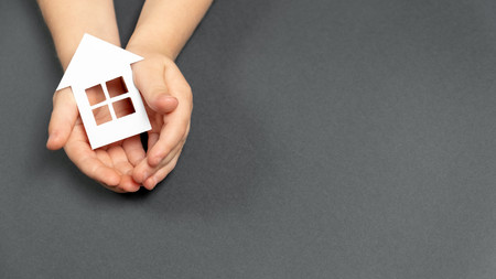 Frau hält ein symbolisches Haus aus Papier in ihren Händen