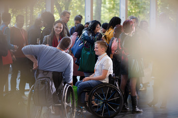 Gruppe von jungen Menschen. Dazwischen zwei Rollstuhlfahrer.