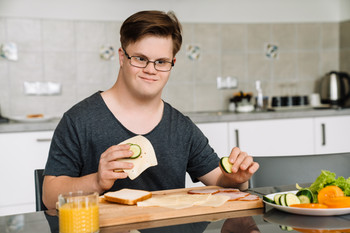 Mensch mit Behinderung sitzt am Frühstückstisch