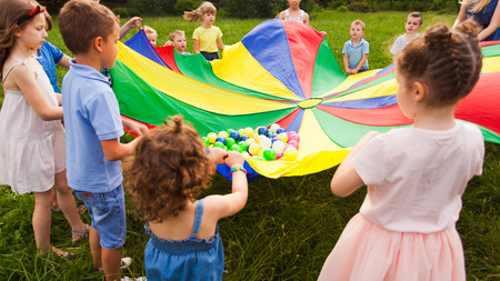 Kinder, die ein Regenbogentuch ausbreiten
