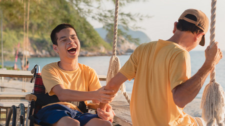Junger Mann im Rollstuhl unterhalten sich lachend am See