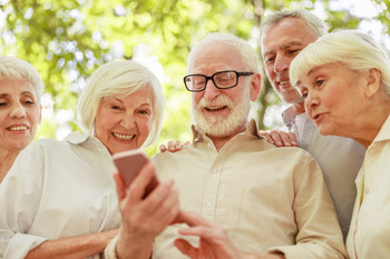 Eine Gruppe von Senioren schaut lachend auf ein Smartphone