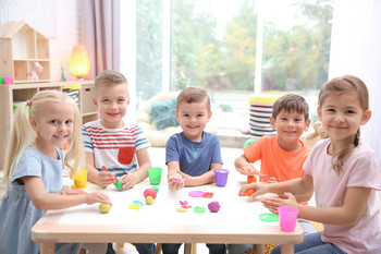 Kinder sitzen in einer Kita an einem Tisch.