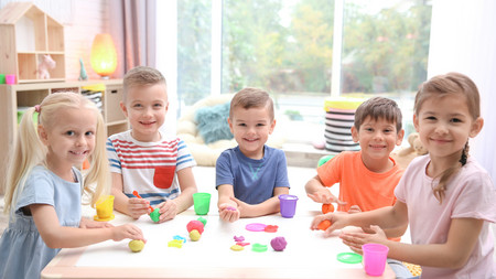 Kinder sitzen in einer Kita an einem Tisch.