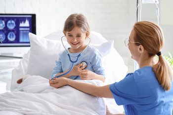 Kind liegt im Krankenhausbett mit einem Stethoskop