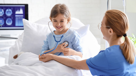 Eine Ärztin untersucht ein Mädchen in einem Krankenhauszimmer
