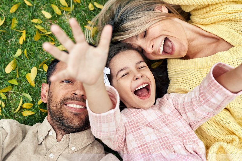 Familie lachend im Gras liegend