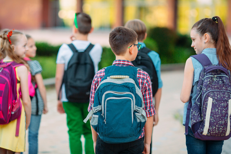 Kinder gehen mit ihren Ranzen zur Schule