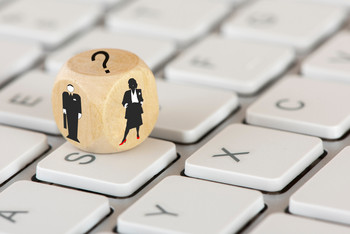 Auf einer Tastatur liegt ein Würfel mit Abbildern von einer Frau, einen Mann und ein Fragezeichen 