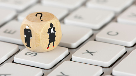 Auf einer Tastatur liegt ein Würfel mit Abbildern von einer Frau, einen Mann und ein Fragezeichen 